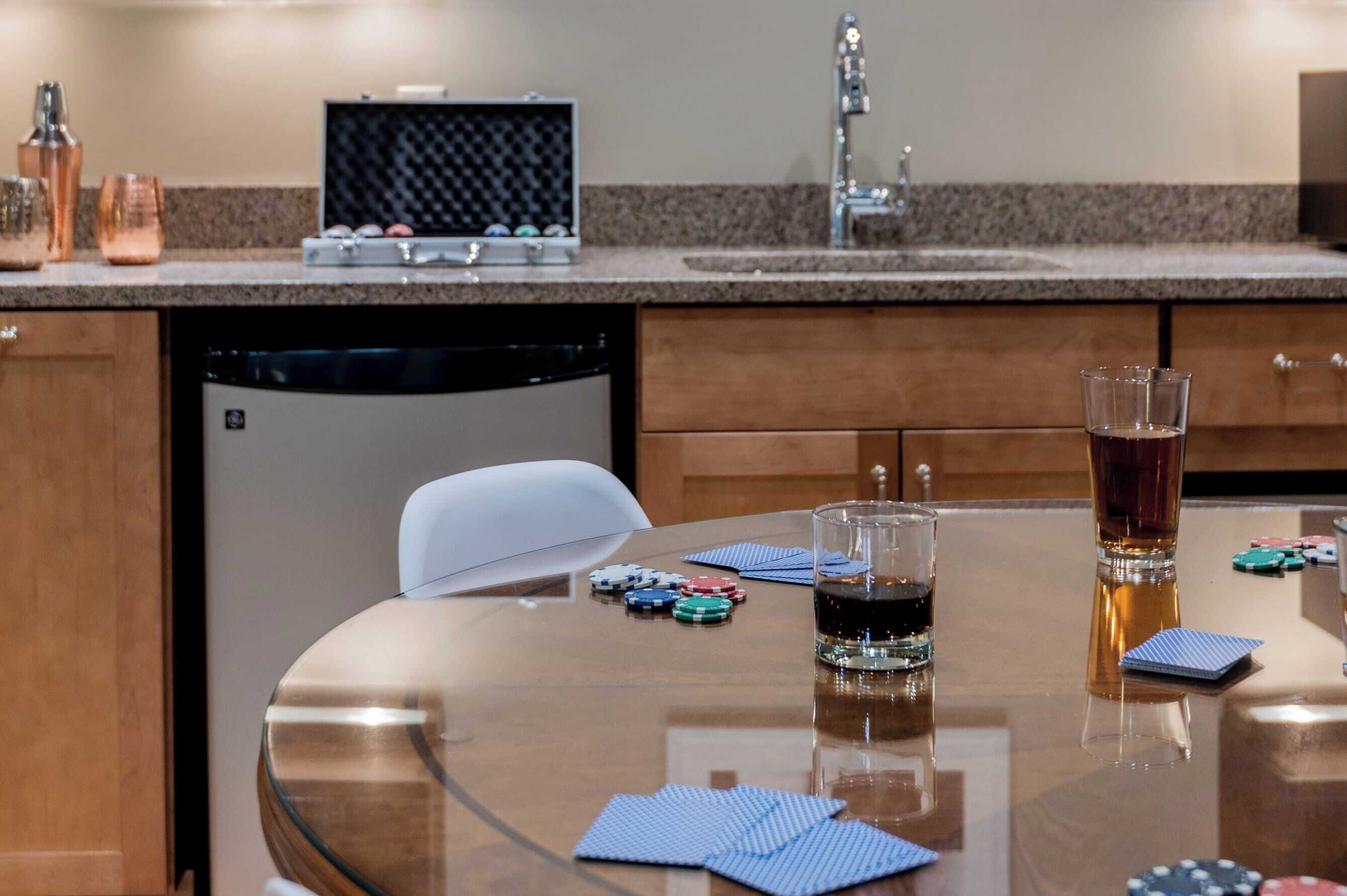 Een keuken met een granieten aanrecht, een vaatwasser, een witte stoel en pokerfiches op tafel.