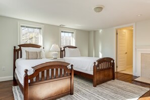 A bedroom with two wooden beds, a nightstand, a lamp, and a patterned rug. - Rockspring by Avantstay Huge Berkshires Estate (Stockbridge)