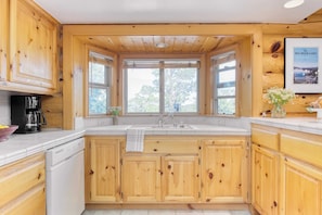 Kitchen with a central island, sink, and window above, offering a view.