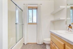 Bathroom features a glass shower enclosure, toilet, and vanity with a mirror.