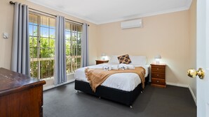 Une chambre à coucher avec un lit, des tables de chevet, une commode et une fenêtre avec des rideaux.