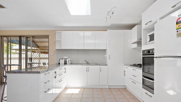 Une cuisine moderne avec des armoires blanches, un four encastré et une cuisinière à gaz.