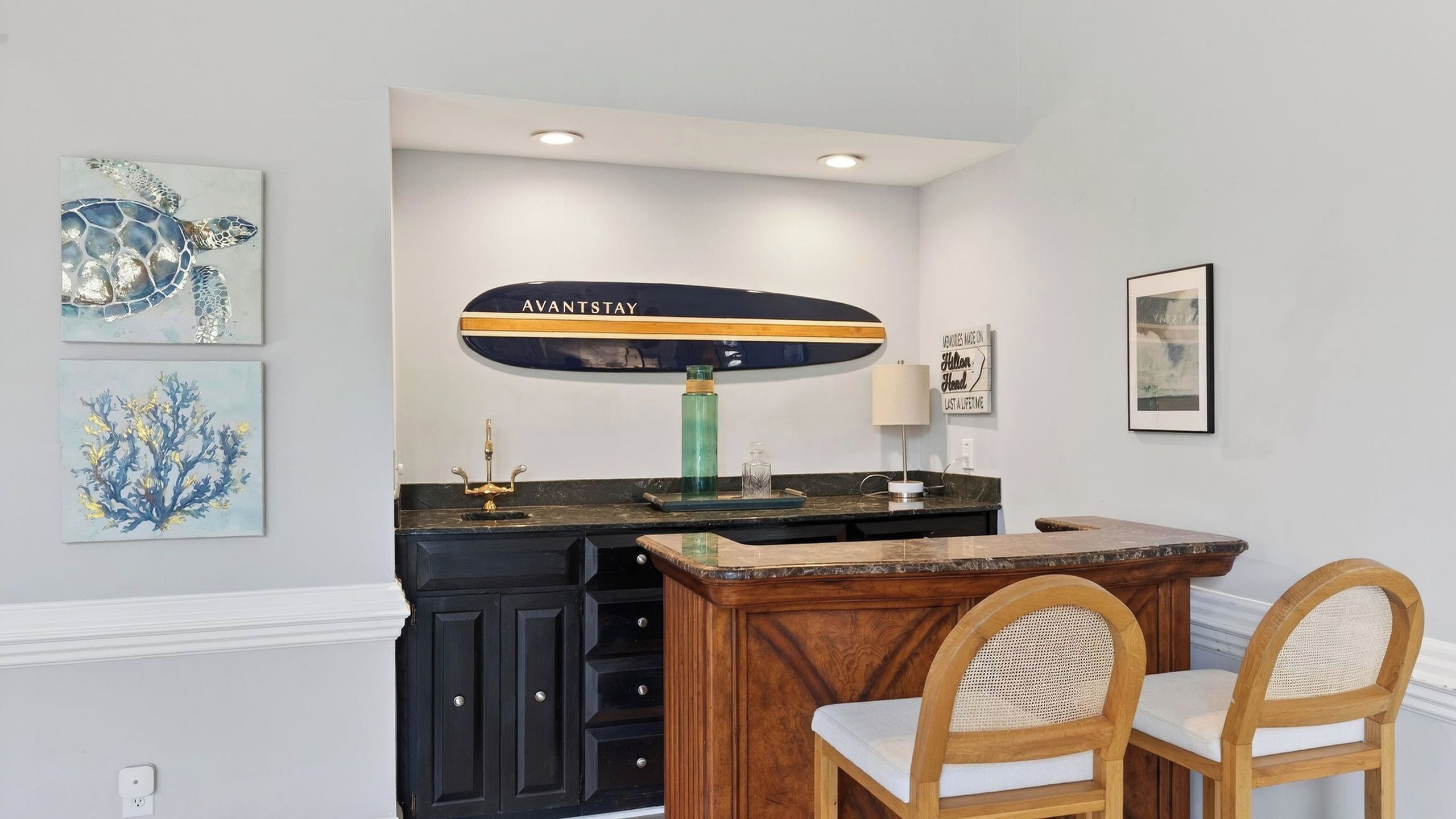 A kitchen with a wooden island, black cabinets, and a green vase.