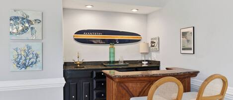 A kitchen with a wooden island, black cabinets, and a green vase.