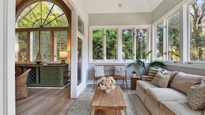 A room with a large arched window, a wooden desk, a sofa, and a coffee table. - Hilton Ivory 15th Hole of Harbourtown Golf Course Private Pool + Hot Tub (Hilton Head Island)