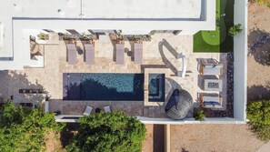 Eine Vogelperspektive zeigt einen modernen Poolbereich im Freien mit mehreren Liegestühlen und einem großen rechteckigen Pool.