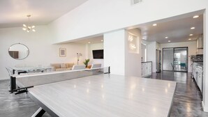 A modern living space with a dining area, kitchen, and a large mirror.