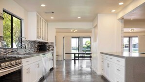 A modern kitchen with white cabinets, a stainless steel stove, and a large island with a granite countertop.