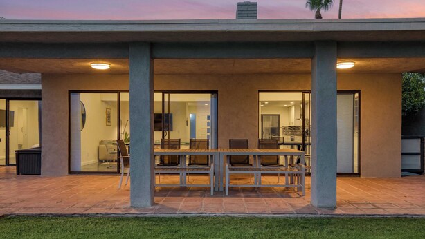 A modern house with a covered patio, large windows, and a dining area.