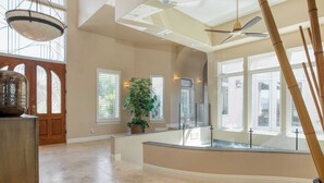 A spacious interior with a high ceiling, large windows, and a central potted plant. - Modern Temecula Mansion w Pool, Hot Tub, Guest House & Valley Views Camila by Avantstay (Temecula)