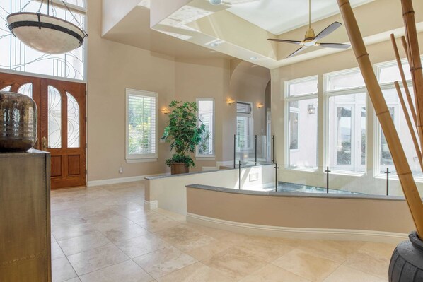 A spacious interior with a high ceiling, large windows, and a central potted plant.