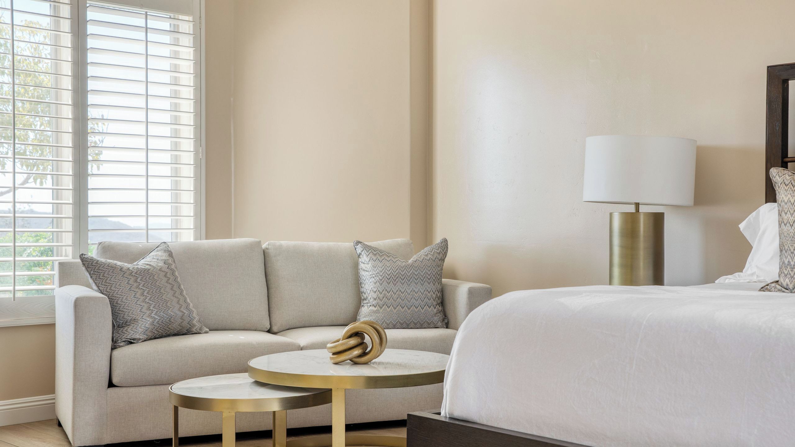 Une chambre d’hôtel avec un canapé, une table basse ronde, un lit et une lampe.