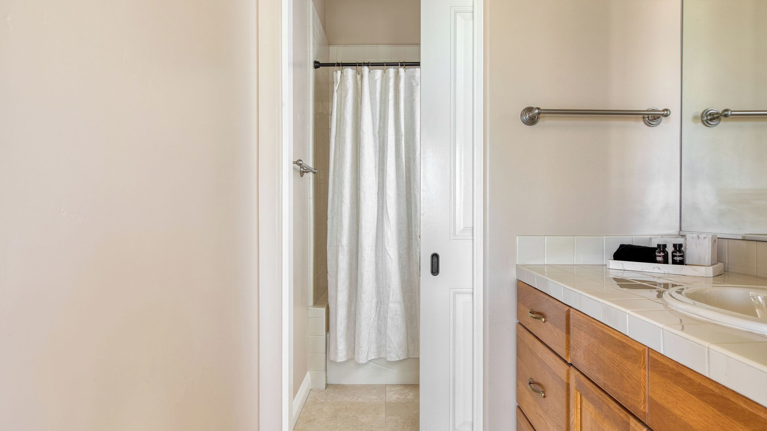Une salle de bain avec un rideau de douche, un lavabo, un miroir et des meubles en bois.