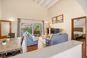 A spacious living area with a sofa, TV, and dining table.
