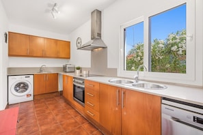 A modern kitchen with wooden cabinets, stainless steel appliances, a built-in oven, and a dishwasher. - SolParc 589 - enjoy and relax (Son Parc)