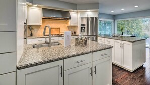 A modern kitchen with granite countertops, stainless steel appliances, and white cabinetry. - Spacious Rochester Home w/ Heated Pool & Hot Tub! (Rochester)