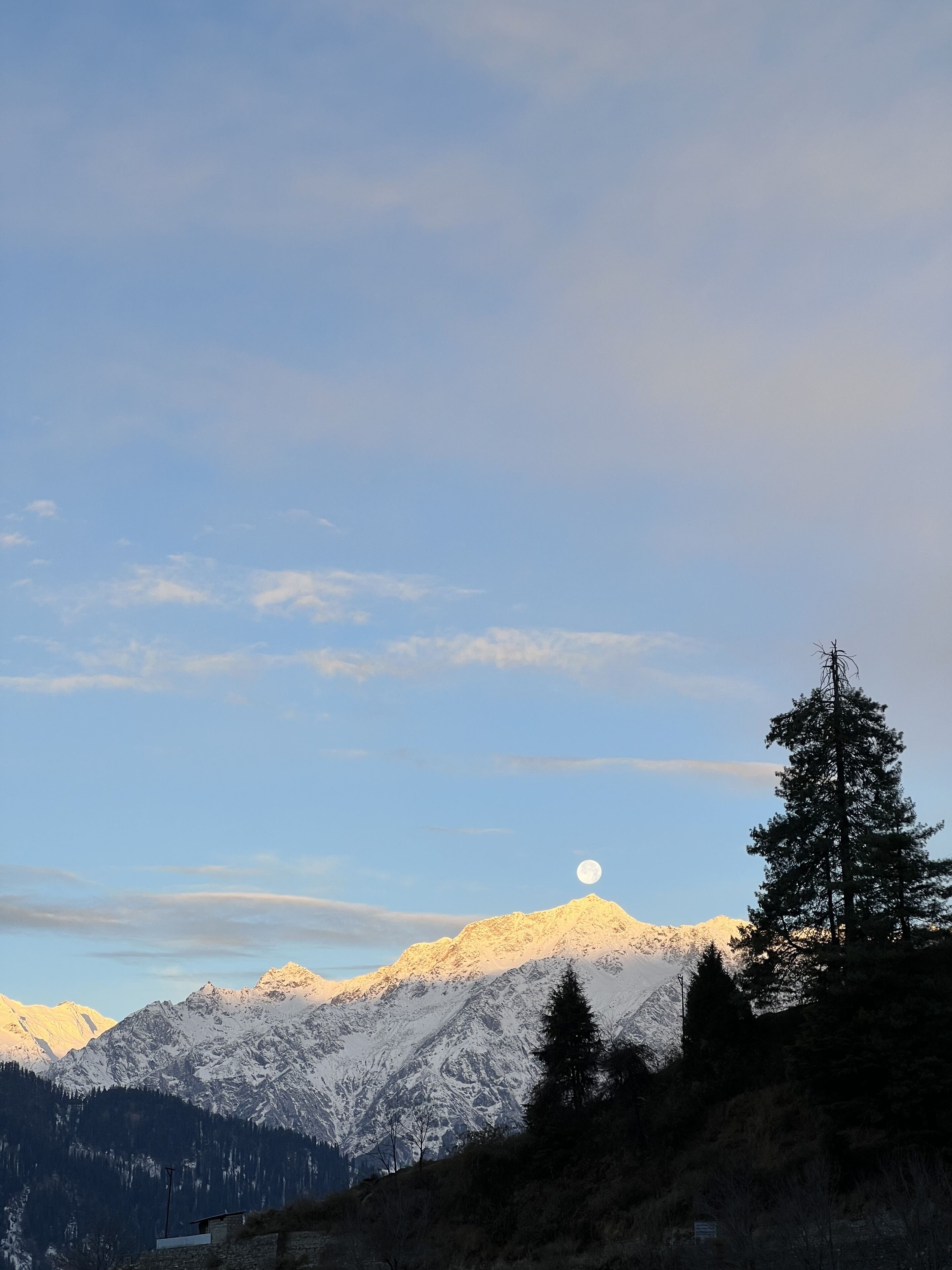 A mountain landscape with a snow-capped peak, a clear sky, and a visible moon.