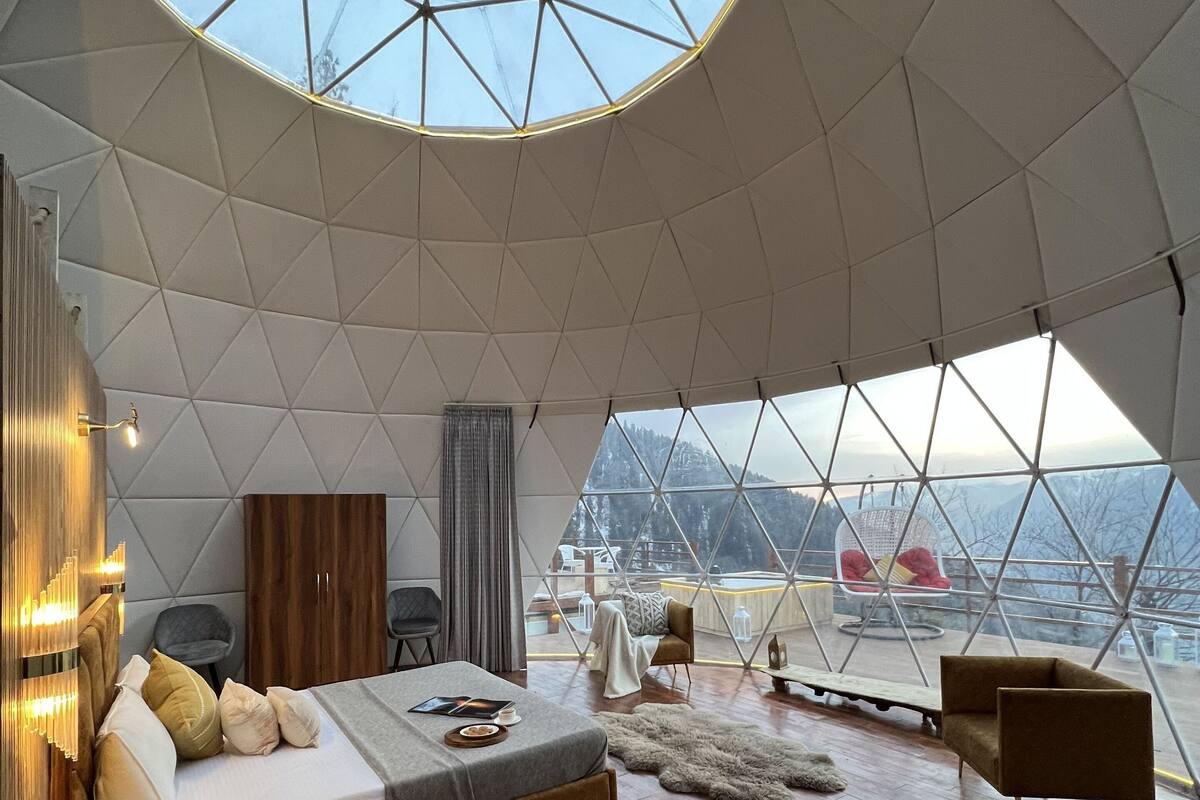 A spacious room with a large skylight, a bed, seating area, and a view of the outdoors.