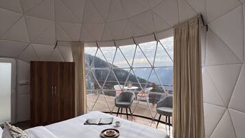 Un dormitorio con una cama grande, un armario de madera y vistas al exterior a través de un techo geométrico.