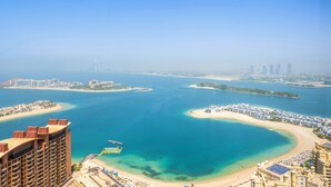 Un paysage urbain côtier avec une vaste étendue d’eau, une plage et de grands immeubles.