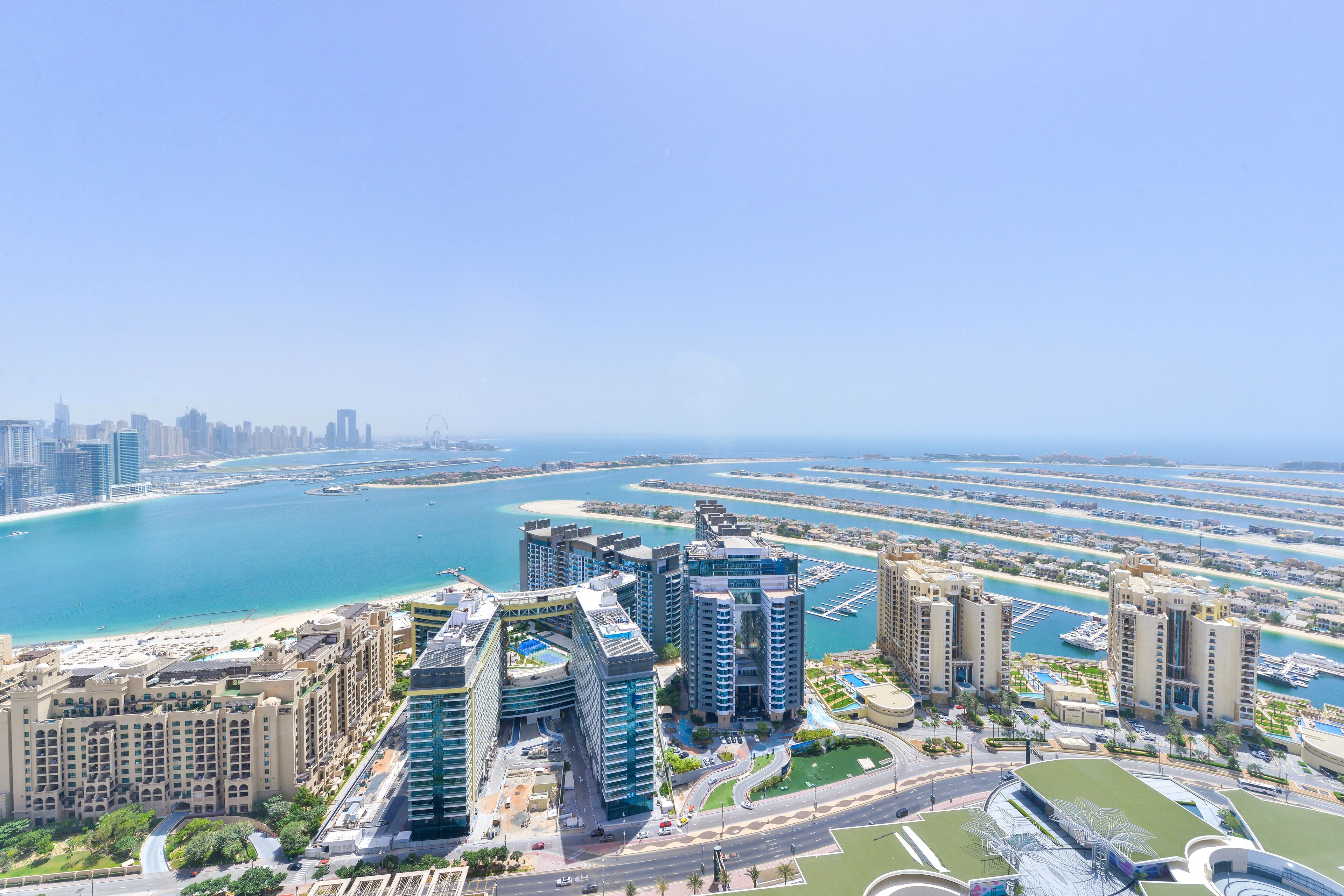 A high-rise hotel with multiple floors, a marina, and a beach in the background.