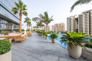 A rooftop pool area with lounge chairs and potted plants, surrounded by high-rise buildings. - Ultra Luxury Palm Tower with Shared Hotel Facilities (Dubai)