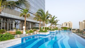 Un hôtel moderne doté d’une grande piscine extérieure, de palmiers et d’une façade au style contemporain.