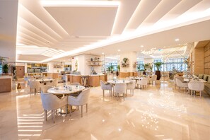 A modern restaurant with a clean, minimalist design, featuring a central bar area, multiple seating options, and a bright, well-lit interior. - Ultra Luxury Palm Tower with Shared Hotel Facilities (Dubai)