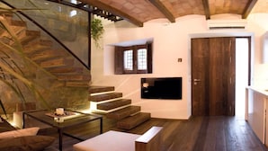 Ein modernes Interieur mit einer Steintreppe, einem an der Wand befestigten Flachbildfernseher und einer Holztür.