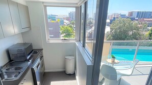 A modern kitchen with a view of a swimming pool and cityscape.