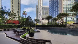 A rooftop pool area with outdoor seating, surrounded by high-rise buildings and a McDonald's sign. - ★StayHere★ 1 Bedroom Avant Fort Bonifacio BGC (Taguig)