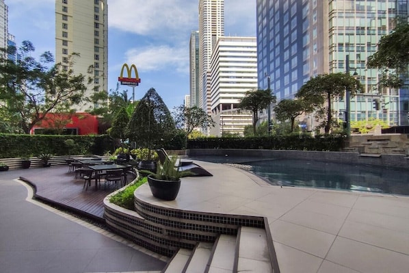 A rooftop pool area with outdoor seating, surrounded by high-rise buildings and a McDonald's sign.