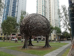 A spherical sculpture with tree-like structures in an urban park setting.