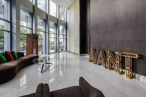 A spacious lobby with a modern design, featuring a sofa, a coffee table, and a large window.