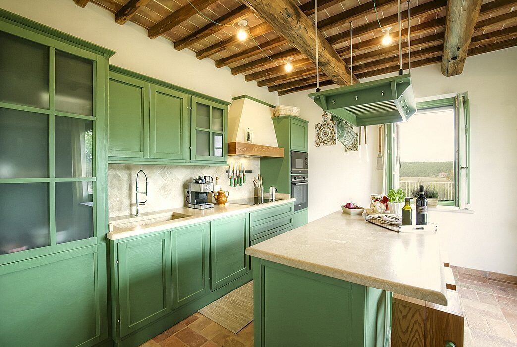 Una cocina con armarios verdes, una isla grande y un techo de madera rústica.