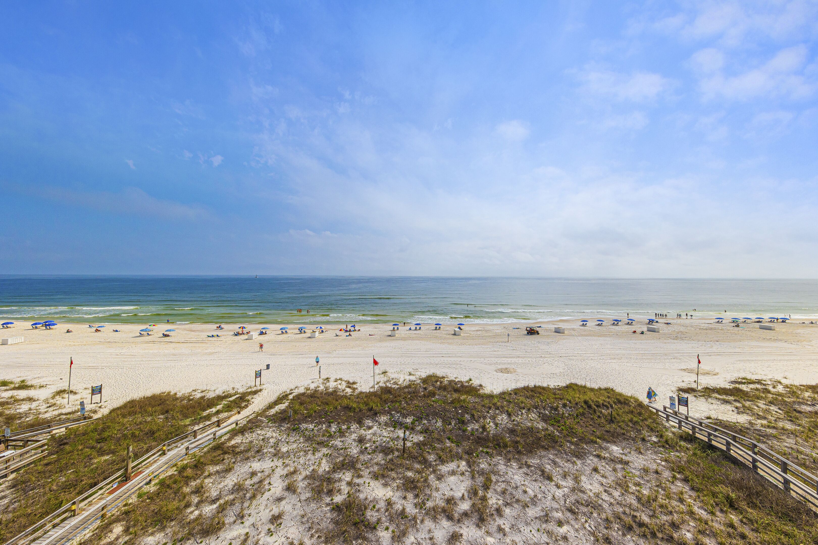 A beach with a wooden boardwalk, sandy beach, and umbrellas.