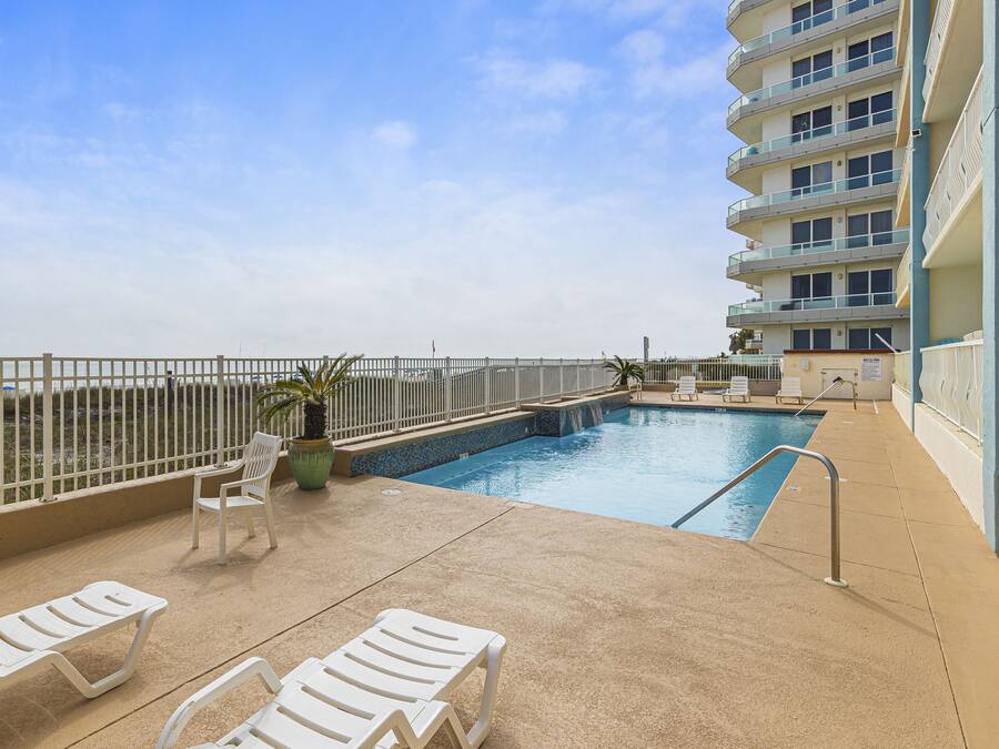A rooftop pool area with lounge chairs, a small pool, and a view of the ocean.