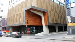 Ein modernes Gebäude mit einer geometrischen Fassade und einem markanten Eingang, mit einem 'ONE WAY'-Schild.