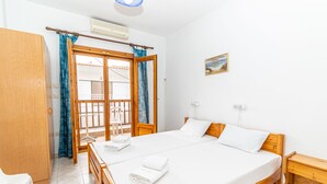 A hotel room with a large bed, wooden furniture, a balcony with a view, and a painting on the wall. - Mina-Maria Apartments (Kassandra)