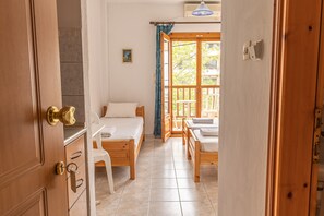 A room with two wooden beds, a white chair, and a wooden desk. - Mina-Maria Apartments (Kassandra)
