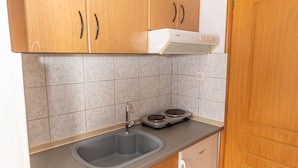 A kitchen with wooden cabinets, a double sink, a stove, and a white refrigerator. - Mina-Maria Apartments (Kassandra)