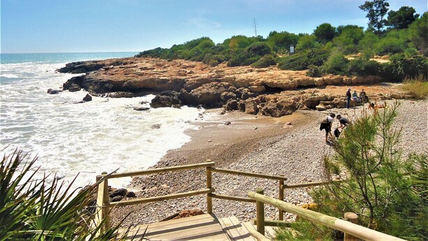 A rocky beach with a wooden walkway leading to a viewing area.