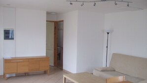 A room with a wooden cabinet, a sofa, a table, and a floor lamp. - Beautiful independent cottage with garden (Contes)