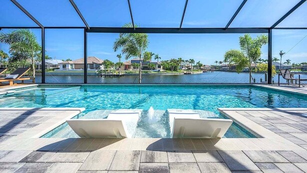 Ein Pool mit klarem, blauem Wasser, umgeben von einer überdachten Liegefläche mit Liegestühlen.