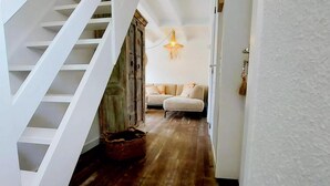 Una escalera conduce a una sala de estar con piso de madera y un sofá.