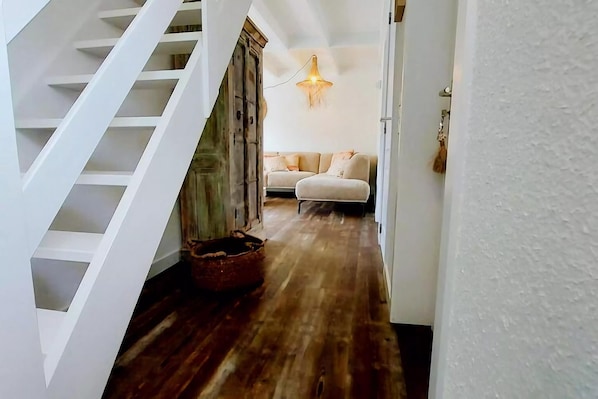 A staircase leading to a living area with a wooden floor and a sofa.