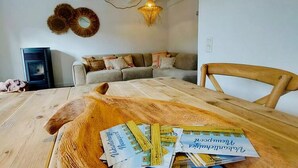 Un comedor con una mesa de madera, un sofá y una lámpara colgante.
