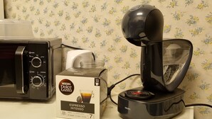 Nescafe Dolce Gusto -espressokone, Krups-kahvinkeitin ja Nescafe Dolce Gusto -tuotepakkaus keittiön työtasolla.