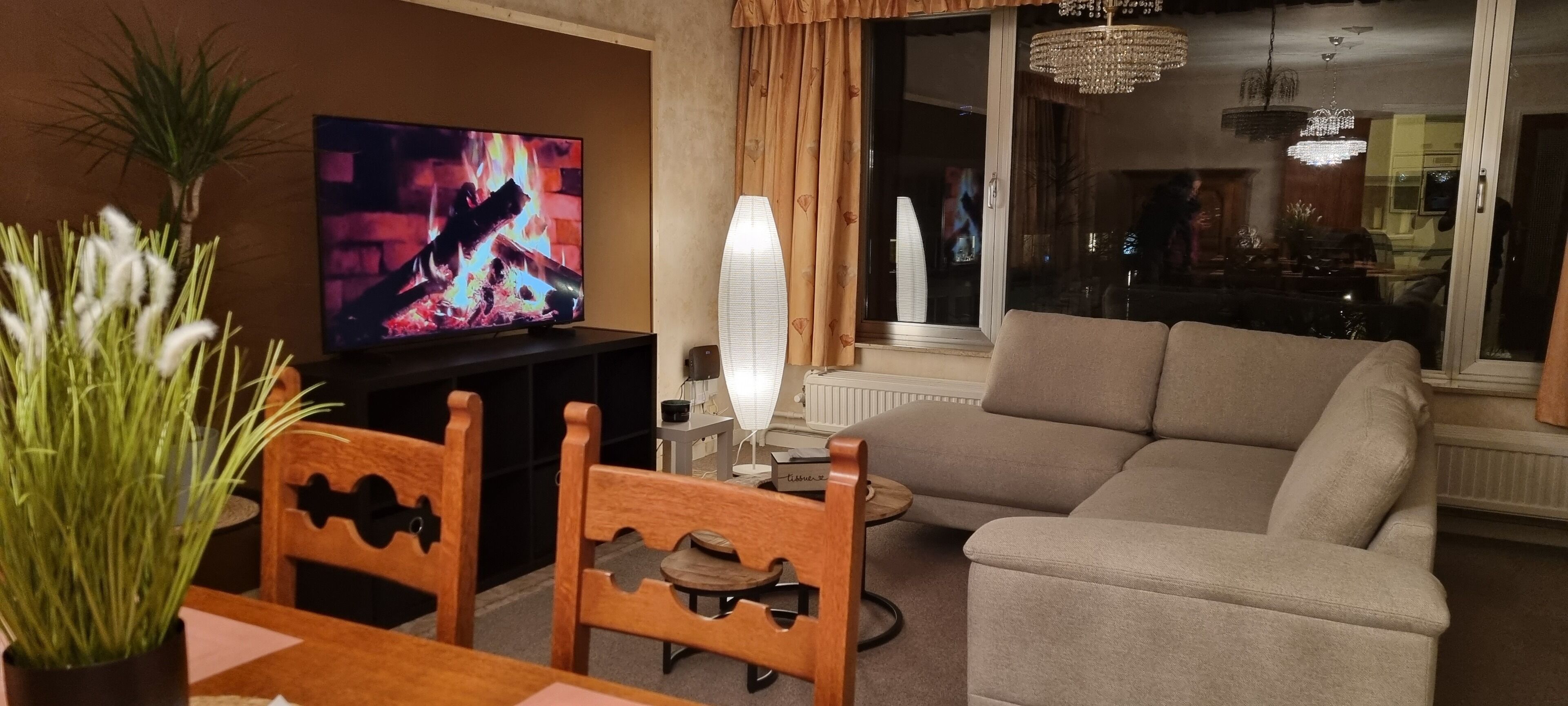 Una sala de estar con televisor, sofá, sillones, una mesita y una planta en maceta.