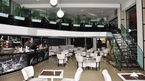 Eine moderne Hotelhalle mit Barbereich, Sitzgelegenheiten und einer Treppe.